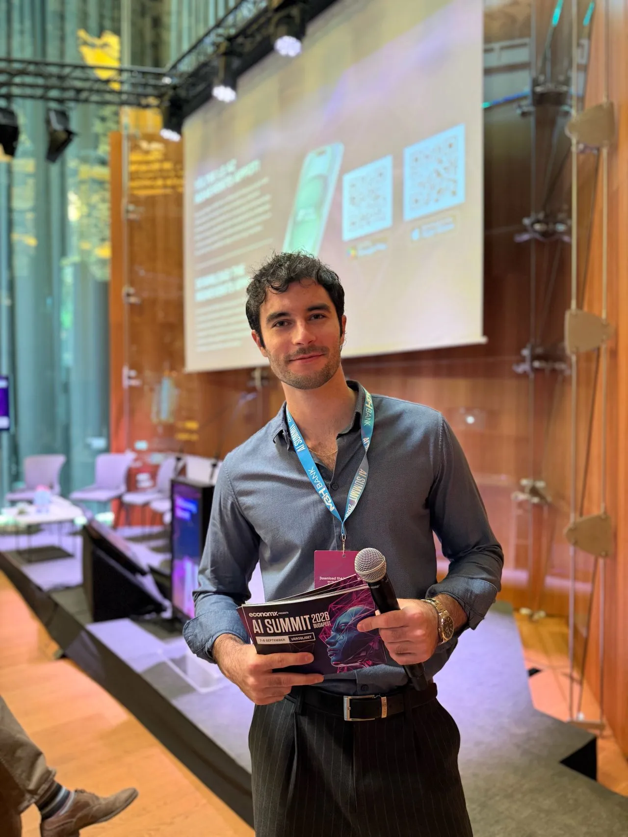 dr. Áron Balázs with a microphone in front of the AI Summit Budapest stage